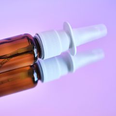 Eine Flasche Nasenspray liegt auf einer spiegelnden Oberfläche