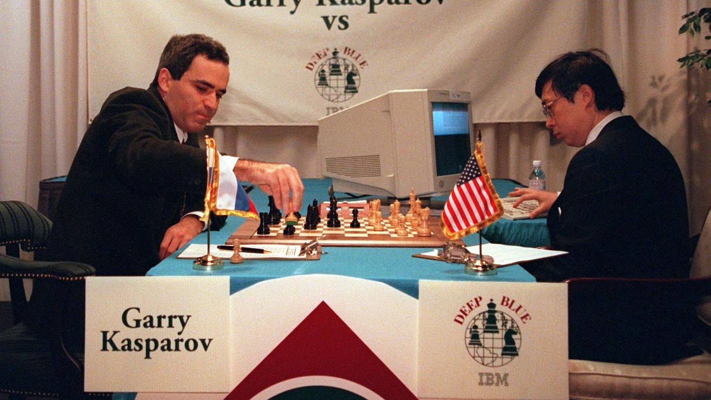 An einem Schachbrett sitzen sich Kasparow und ein Mann mit einem PC gegenüber.