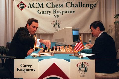 An einem Schachbrett sitzen sich Kasparow und ein Mann mit einem PC gegenüber.