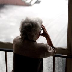 Eine Person steht an einem Geländer und hält sich die Hände an den Kopf