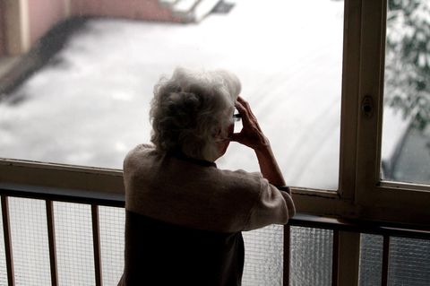 Eine Person steht an einem Geländer und hält sich die Hände an den Kopf