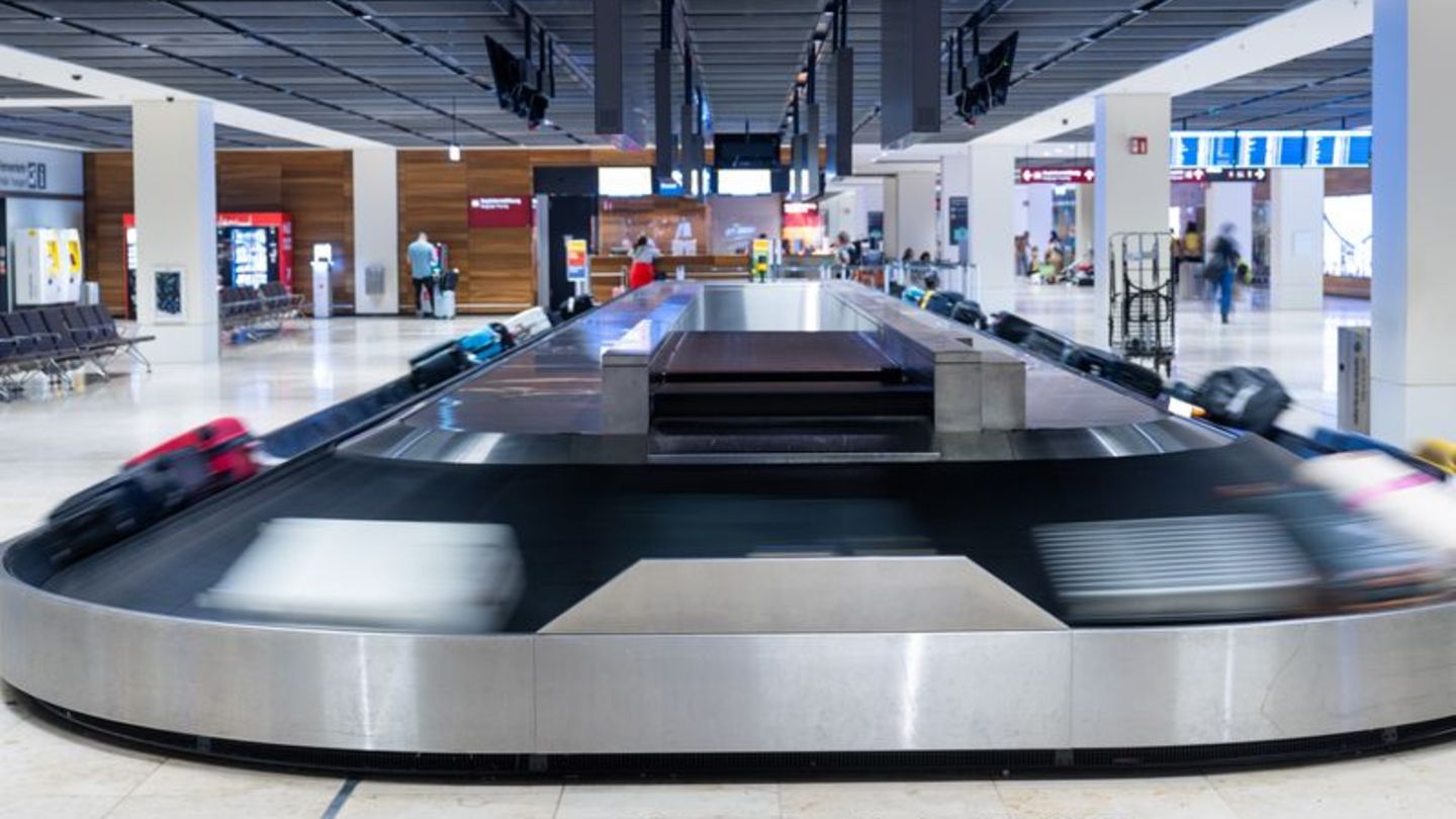 Ein Gepäckband läuft an und transportiert Koffer am Flughafen