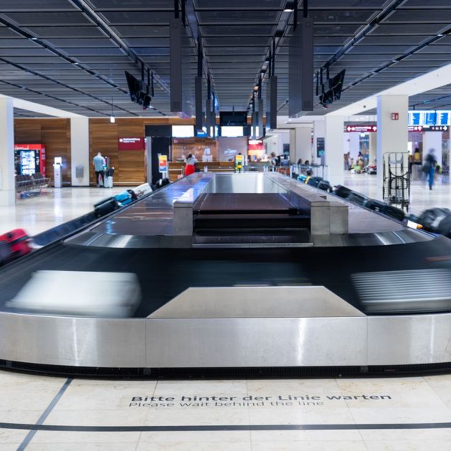 Ein Gepäckband läuft an und transportiert Koffer am Flughafen