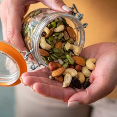 Eine Person schüttet Studentenfutter in ihre Hand