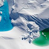 Auf der Oberfläche von Eisflächen und -bergen sammelt sich im Lauf des Sommers Schmelzwasser. Auf dem Drohnenbild gut zu erkennen sind die unterschiedlichen Farbtöne der Tümpel. Klares Meerwasser (links) erscheint in Azurblau, nährstoff- und algenreiches Meerwasser in Grüntönen. Auch dieses Bild entstand in der Diskobucht.