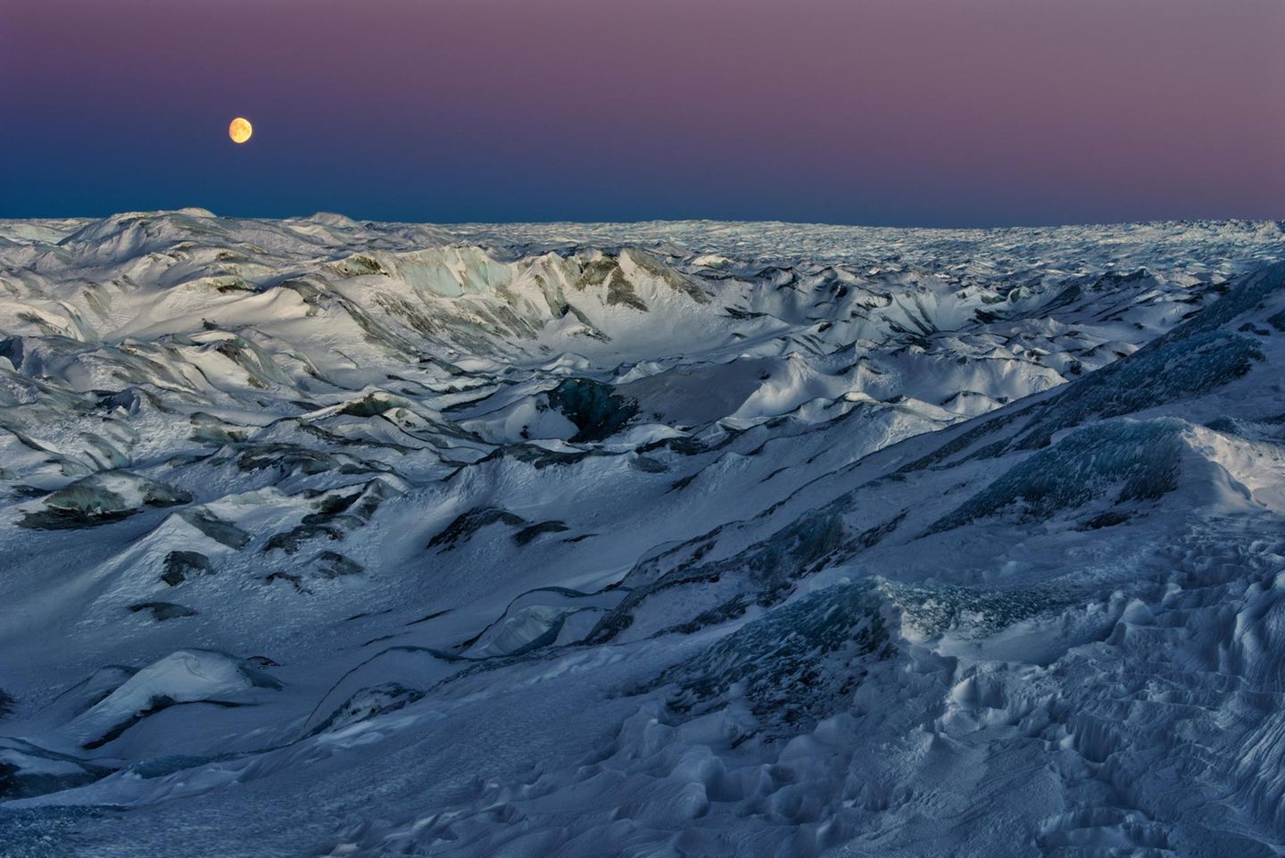 Beim Point 660 nahe Kangerlussuaq öffnet sich der Blick auf das unabsehbare Inlandeis. Ein unwirklicher Anblick, zumal im fahlen Licht des aufgehenden Mondes. Man stehe in solchen Momenten "vor der Frage, ob man noch auf der Erde weilt – oder sich längst auf einem fernen Eisplaneten jenseits der Grenzen unseres Sonnensystems verirrt hat", schreibt der Fotograf.
