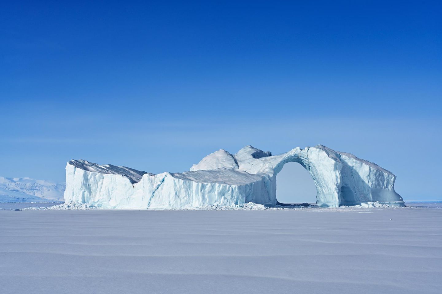 Der Uummannaq-Fjord an der Westküste Grönlands: Wenn im arktischen Herbst die Temperaturen unter den Gefrierpunkt fallen, werden treibende Eisberge an Ort und Stelle eingefroren. Ob der markante Bogen dieses Eisriesen den folgenden Sommer überleben wird?