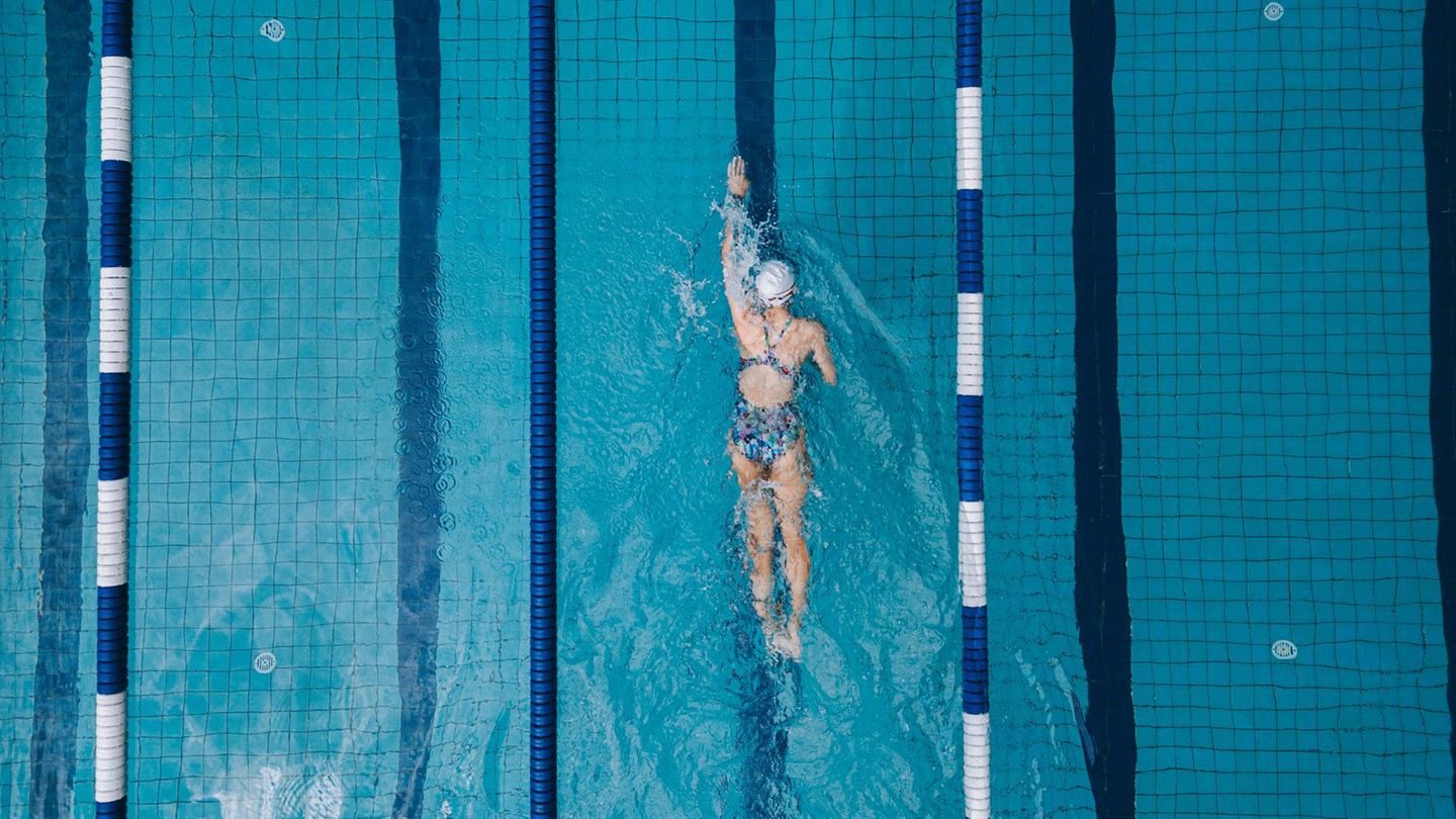 Schwimmende Frau im Becken eines Hallenbads