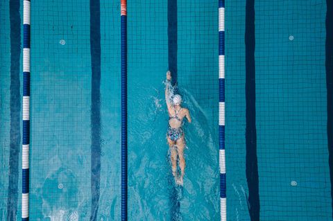 Schwimmende Frau im Becken eines Hallenbads