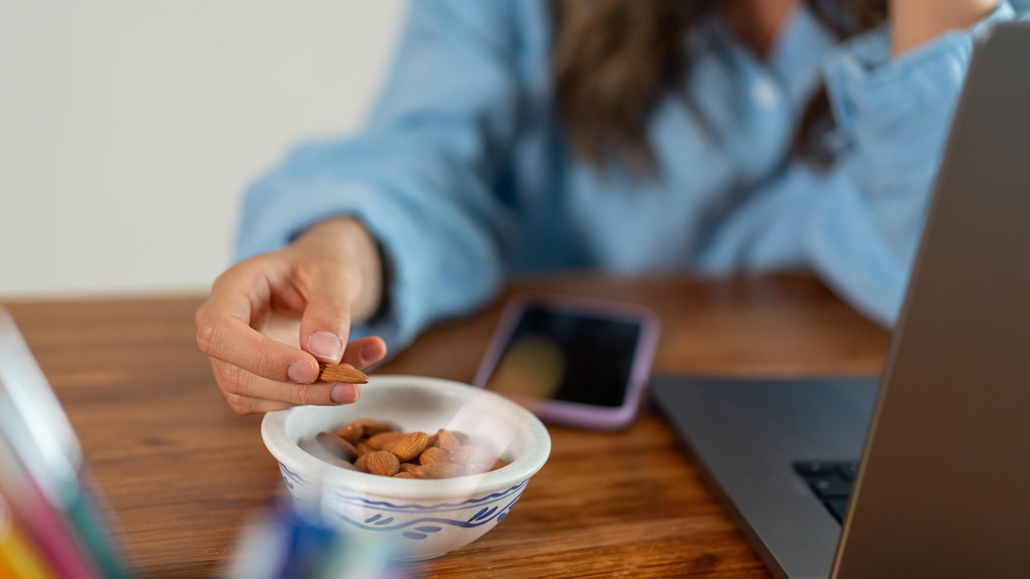 Frau isst Mandeln während der Arbeit