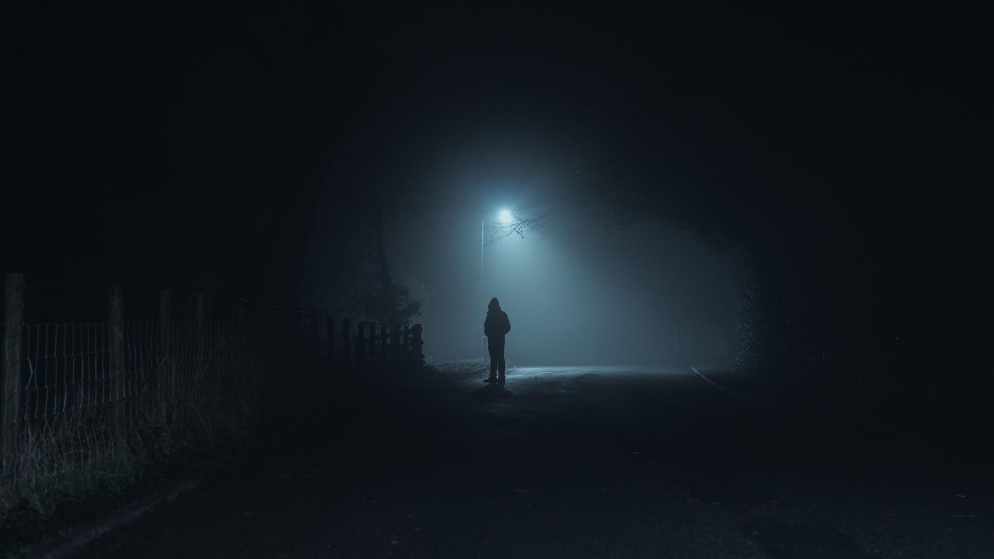 Mann steht in der Dunkelheit auf einer Strasse