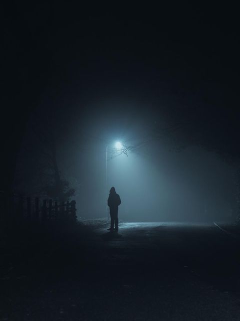 Mann steht in der Dunkelheit auf einer Strasse