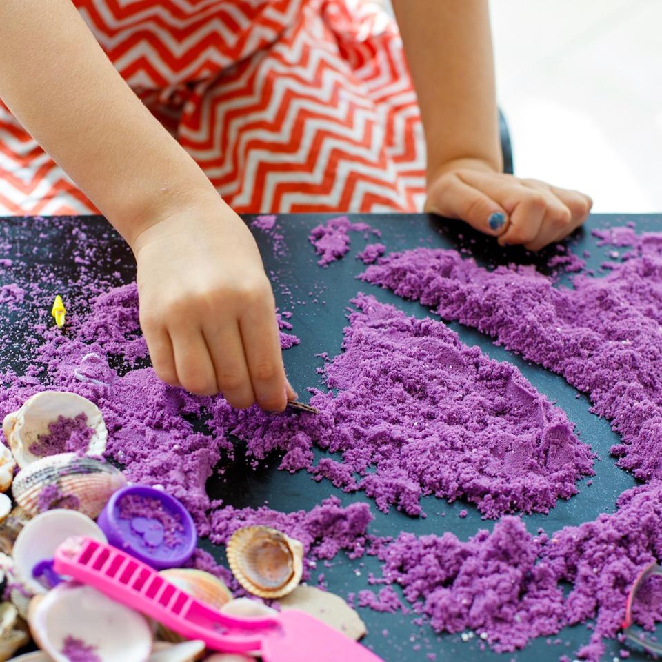Ein Kind spielt mit farbigem Sand