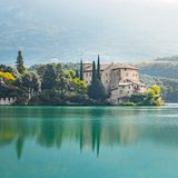 Schon von Weitem spiegelt sich Castel Toblino im türkisblauen Wasser. Zahlreiche Legenden ranken sich um das romantische Schloss, das auf einer Felszunge in den Toblinosee hineinragt. Feen hätten hier gelebt, außerdem soll es ein Liebesversteck des Fürstbischofs Carlo Emanuele Madruzzo und seiner Geliebten Claudia Particella gewesen sein. Im Schloss befindet sich heute ein elegantes Restaurant mit Bar. Das historische Ambiente macht es zu einem besonders stimmungsvollen Ort. Die schönste Zeit, dieses Stück Trentino zu entdecken, ist der Mai: Dann blüht das Valle dei Laghi, das Tal der Seen, nach den stillen Wintermonaten in frischen Farben auf.
