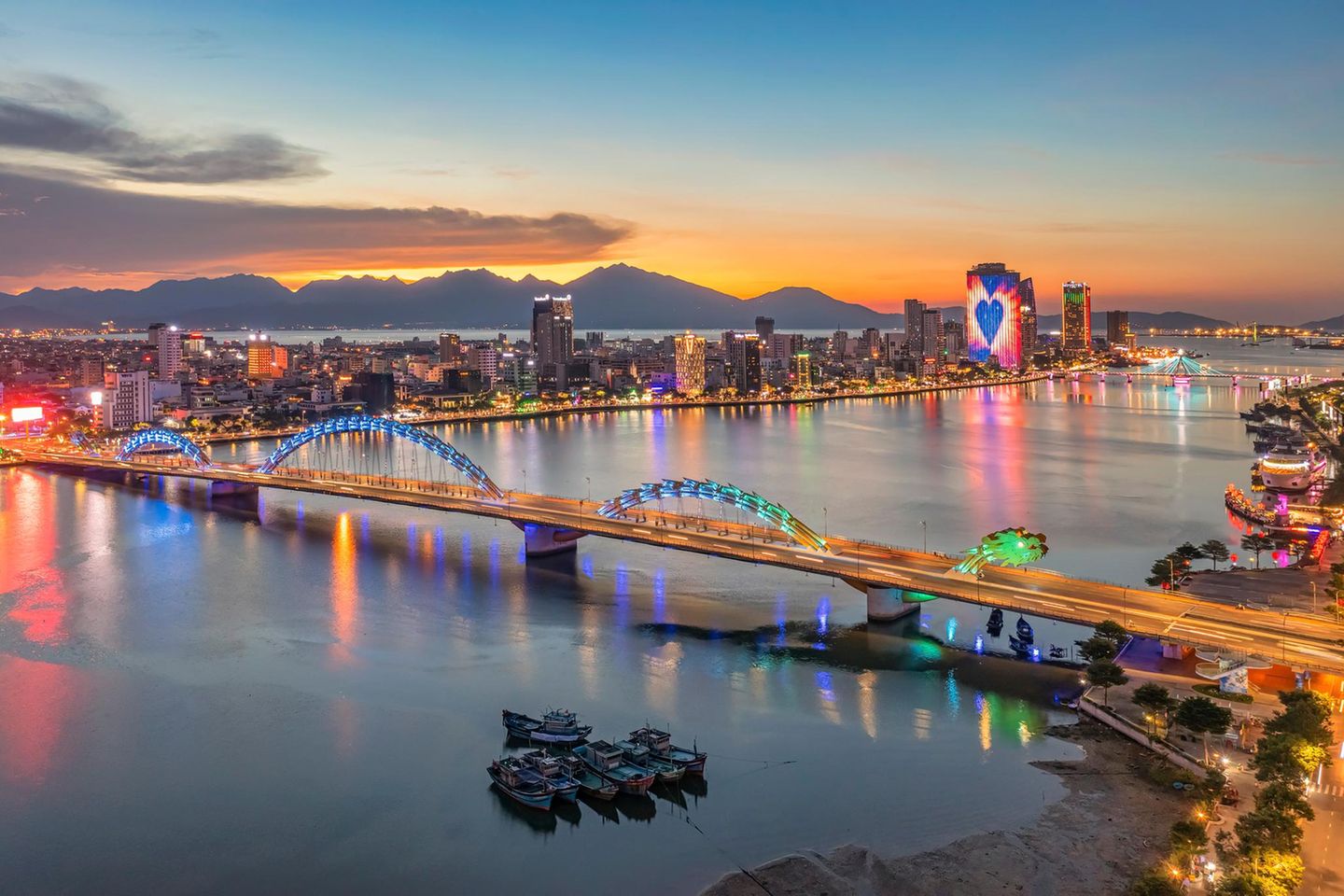 Für Vietnam-Kenner ist sie längst kein Geheimtipp mehr, und doch steht Da Nang, immerhin die größte Stadt Zentralvietnams, im Schatten von Hanoi, Ho-Chi-Minh-Stadt oder Hoi An. Einst lag sie im Einflussbereich des Cham-Reiches, dessen kulturelles Erbe heute im Da Nang Museum of Cham Sculpture gewürdigt wird. Während der französischen Kolonialzeit war die Hafenstadt ein wichtiger Stützpunkt, später ein zentraler Schauplatz des Vietnamkriegs. Heute finden Reisende hier eine dynamische Metropole mit gläsernen Hochhausfassaden und lebendiger Uferpromenade. Wahrzeichen der Stadt ist die bunt illuminierte Drachenbrücke über den Han-Fluss, die am Wochenende abends spektakulär Feuer und Wasser speit. Bei Surfern und Badegästen sind die langen Sandstrände wie der legendäre China Beach beliebt. Unbedingt sehenswert sind außerdem die nahegelegenen Marmorberge mit ihren Aussichtspunkten, Tempeln, Höhlen und Grotten.