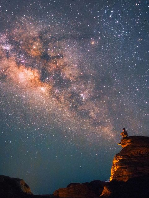 Ein Mann blickt in den Nachthimmel, wo sich die Milchstraße zeigt
