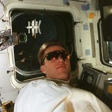 Astronaut Brent W. Jett am Fenster des Raumschiffs Atlantis, die Mir ist im Weltall zu sehen