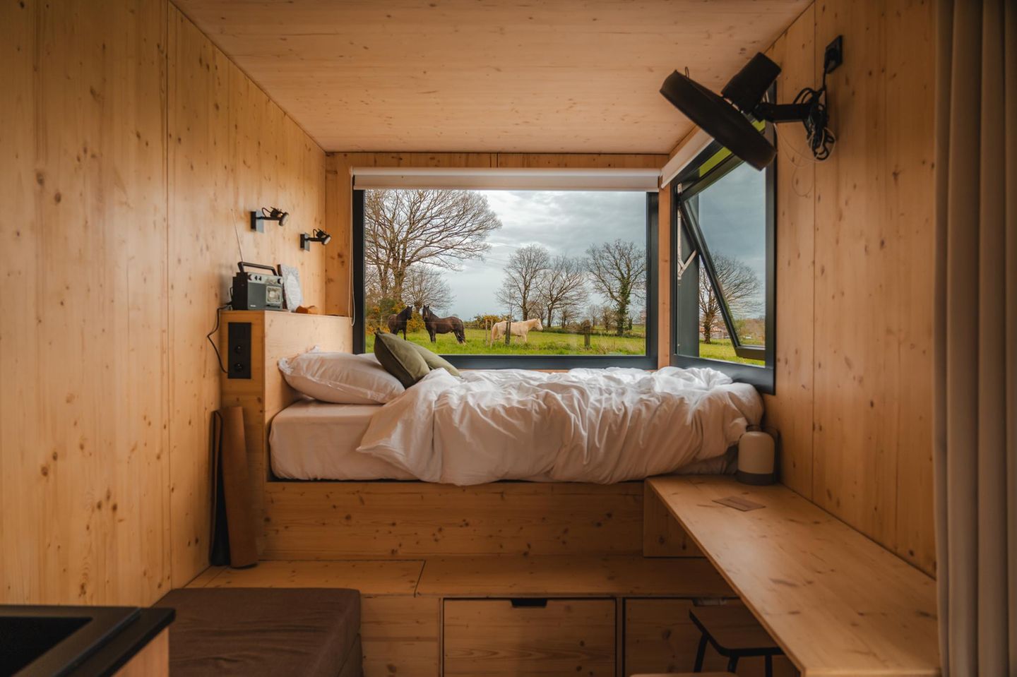 Bett im Tiny House mit Pferden im Hintergrund, Parcel Tiny House