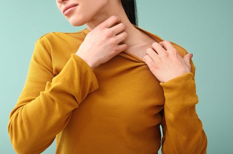 Eine Frau kratzt sich am Hals