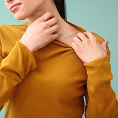 Eine Frau kratzt sich am Hals