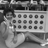 Eine Frau telefoniert vor einem Meter langen Telefon