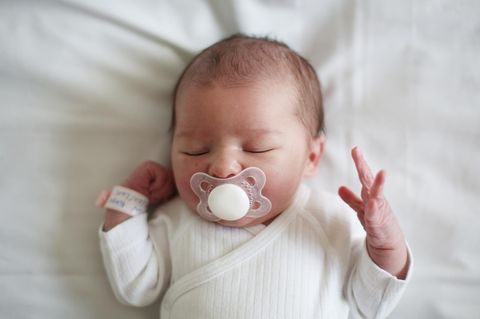Blick von oben: Neugeborenes Baby schläft mit Schnuller