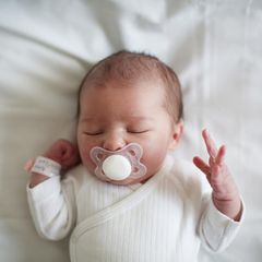 Blick von oben: Neugeborenes Baby schläft mit Schnuller