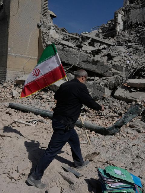 Mann trägt Iran-Fahne vorbei an Trümmern