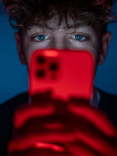 Ein 13-jähriger Junge starrt auf seinen Smartphone-Bildschirm