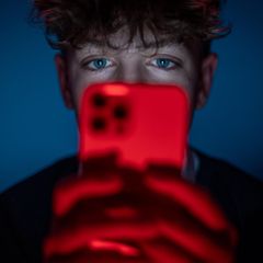 Ein 13-jähriger Junge starrt auf seinen Smartphone-Bildschirm