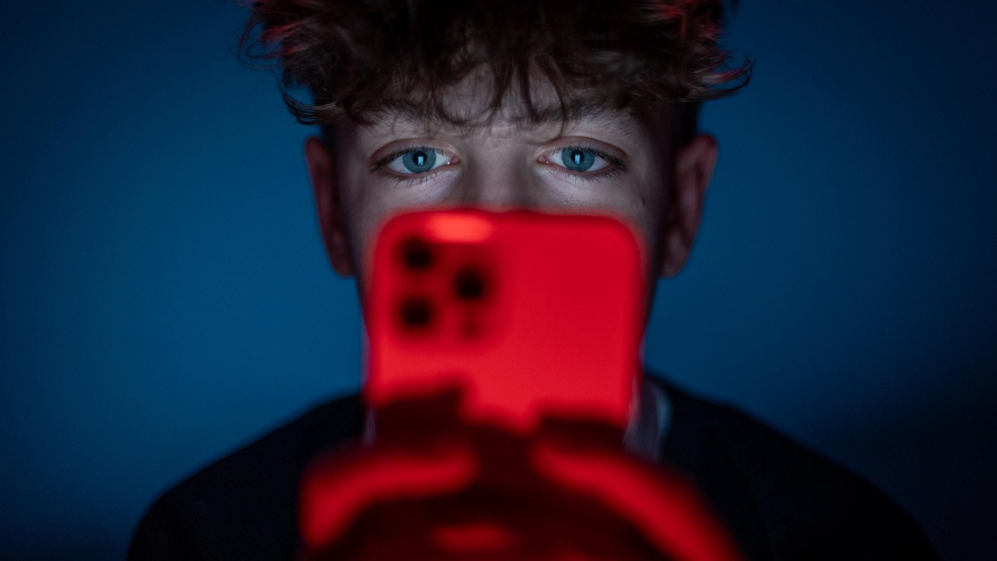 Ein 13-jähriger Junge starrt auf seinen Smartphone-Bildschirm