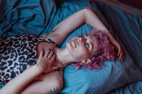 Eine junge Frau liegt verträumt auf ihrem Bett