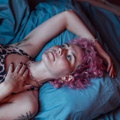 Eine junge Frau liegt verträumt auf ihrem Bett