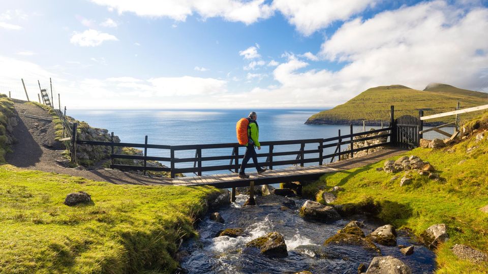 Wanderer auf einer Holzbrücke auf den Faröer Inseln