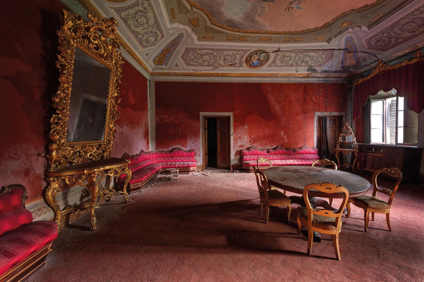 Dieses rote Wohnzimmer beherbergte einst eine italienische Arztfamilie. In dem toskanischen Palazzo ist auch das ehemalige Arbeitszimmer mit Bücherregal, Urkunden, Briefen und persönlichen Gegenständen erhalten geblieben.