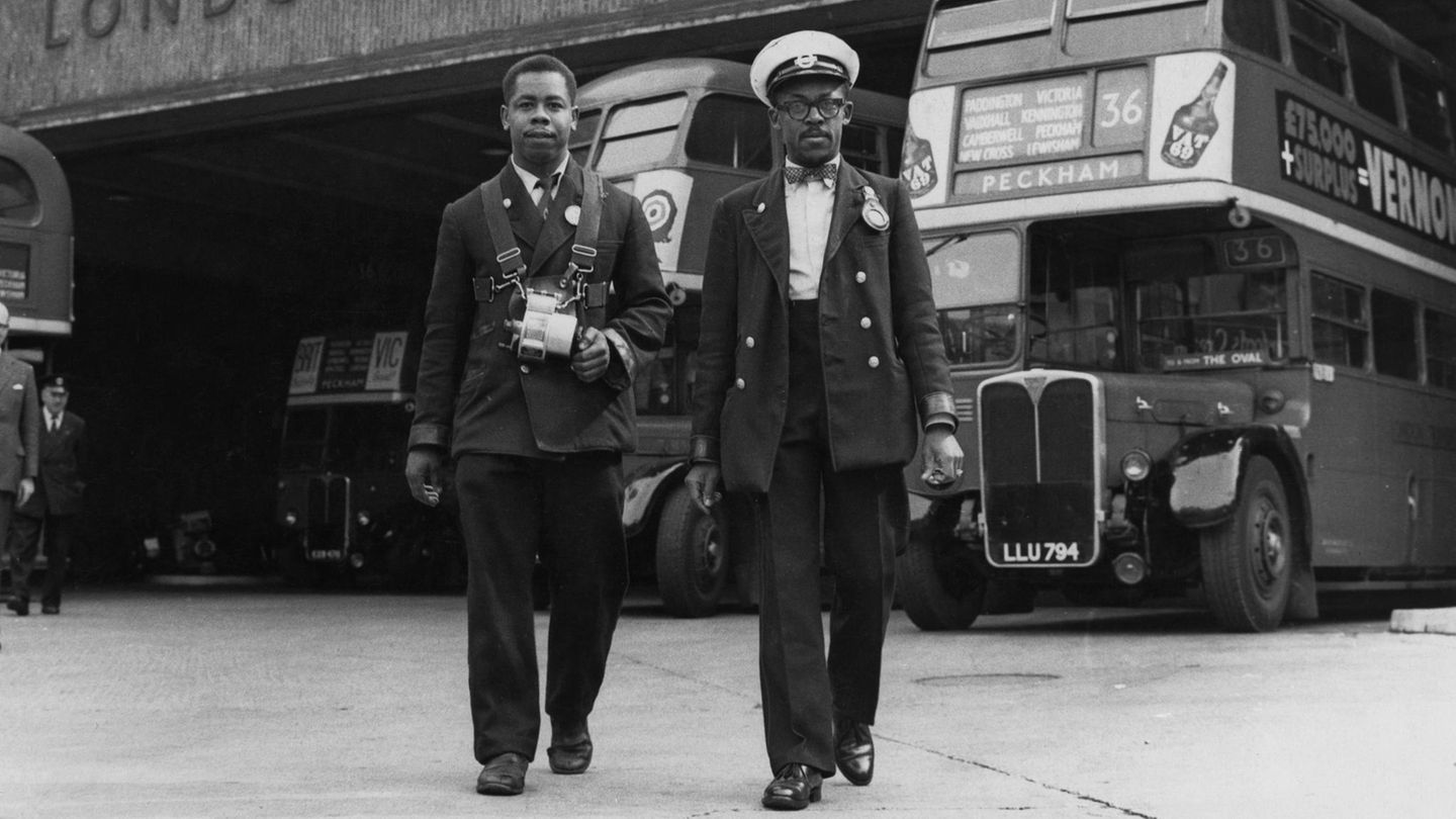 Ein Schaffner und ein Ticketkontrolleur stehen vor einem Londoner Doppeldeckerbus, Schwarz-Weiß-Aufnahme von 1957