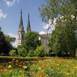 Stiftskirche Admont, davor Bäume und Wiese mit bunten Blumen