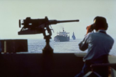 Mann schaut durch Fernglas auf Schiff