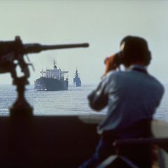 Mann schaut durch Fernglas auf Schiff