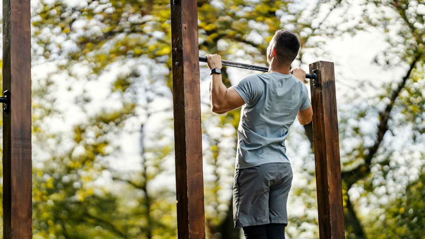 Mann macht Klimmzug im Wald an einer Stange