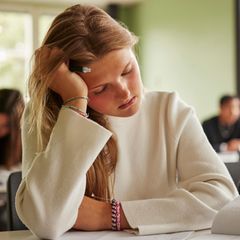 Eine müde Schülern stützt ihren schweren Kopf