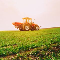 Ein Bauer auf seinem Traktor düngt ein Weizenfeld