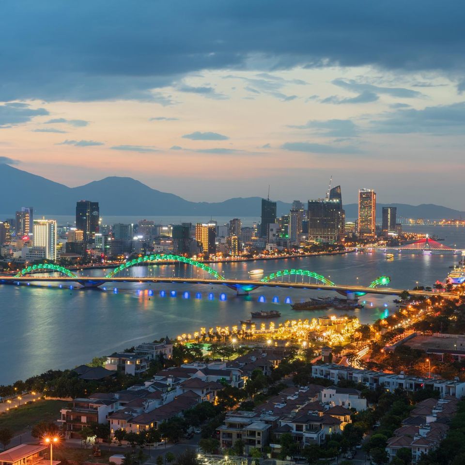 Der goldene Drache über dem Han-Fluss ist schon am Tag ein imposanter Anblick. Nachts leuchtet er spektakulär, spuckt am Wochenende sogar Feuer und Wasser – zur Freude von Reisenden und Einheimischen. Die 666 Meter lange Drachenbrücke (Cau Rong) verbindet den älteren Teil Da Nangs auf dem Festland mit dem jungen Viertel auf der Halbinsel. Wer vom Flughafen in die Stadt fährt, begegnet als Erstes ihrem feurigen Drachenkopf. Noch ist die Küstenstadt touristisch weniger bekannt als Hanoi, Ho-Chi-Minh-Stadt oder die alte Kaiserstadt Huê. Dabei hat Da Nang viel zu bieten: Strandtage, Stadtbummel, Nachtleben und Ausflüge ins grüne Umland lassen sich hier mühelos verbinden. Kulturelle Sehenswürdigkeiten wie die 67 Meter hohe Lady-Buddha-Statue, das Cham-Museum, die Ruinen der Dien-Hai-Zitadelle und die rosafarbene Kathedrale erzählen von einer bewegten Vergangenheit.