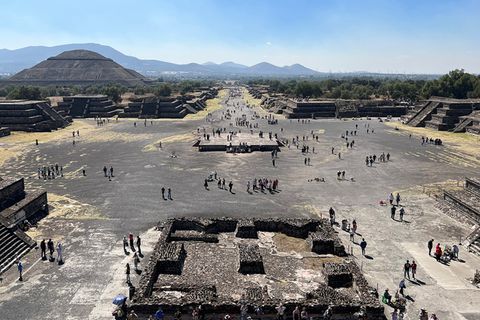 Blick über Ruinen von Teotihuacán: vorne ein Platz mit großem Podest, hinten eine von Stufenpyramiden gesäumte Straße