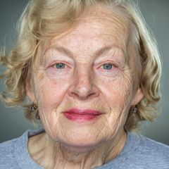 Nahaufnahme einer älteren Frau mit faltigem Gesicht vor grauem Hintergrund