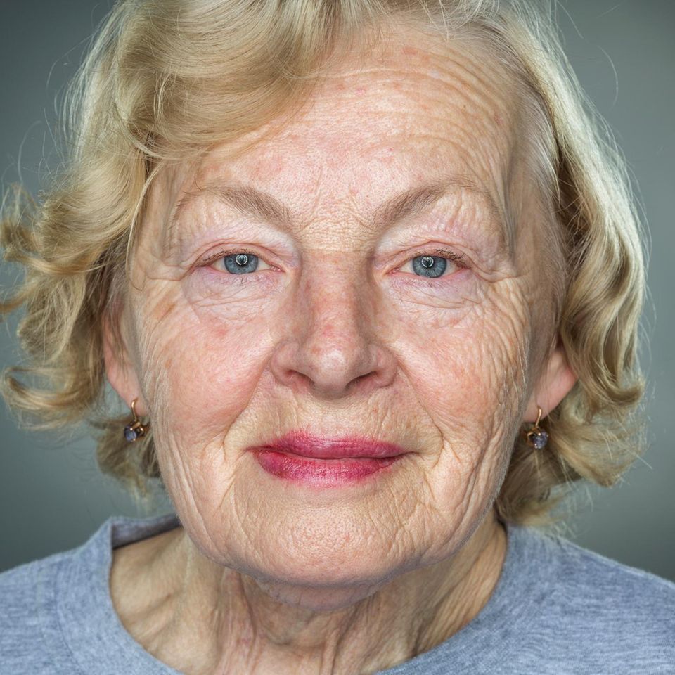 Nahaufnahme einer älteren Frau mit faltigem Gesicht vor grauem Hintergrund