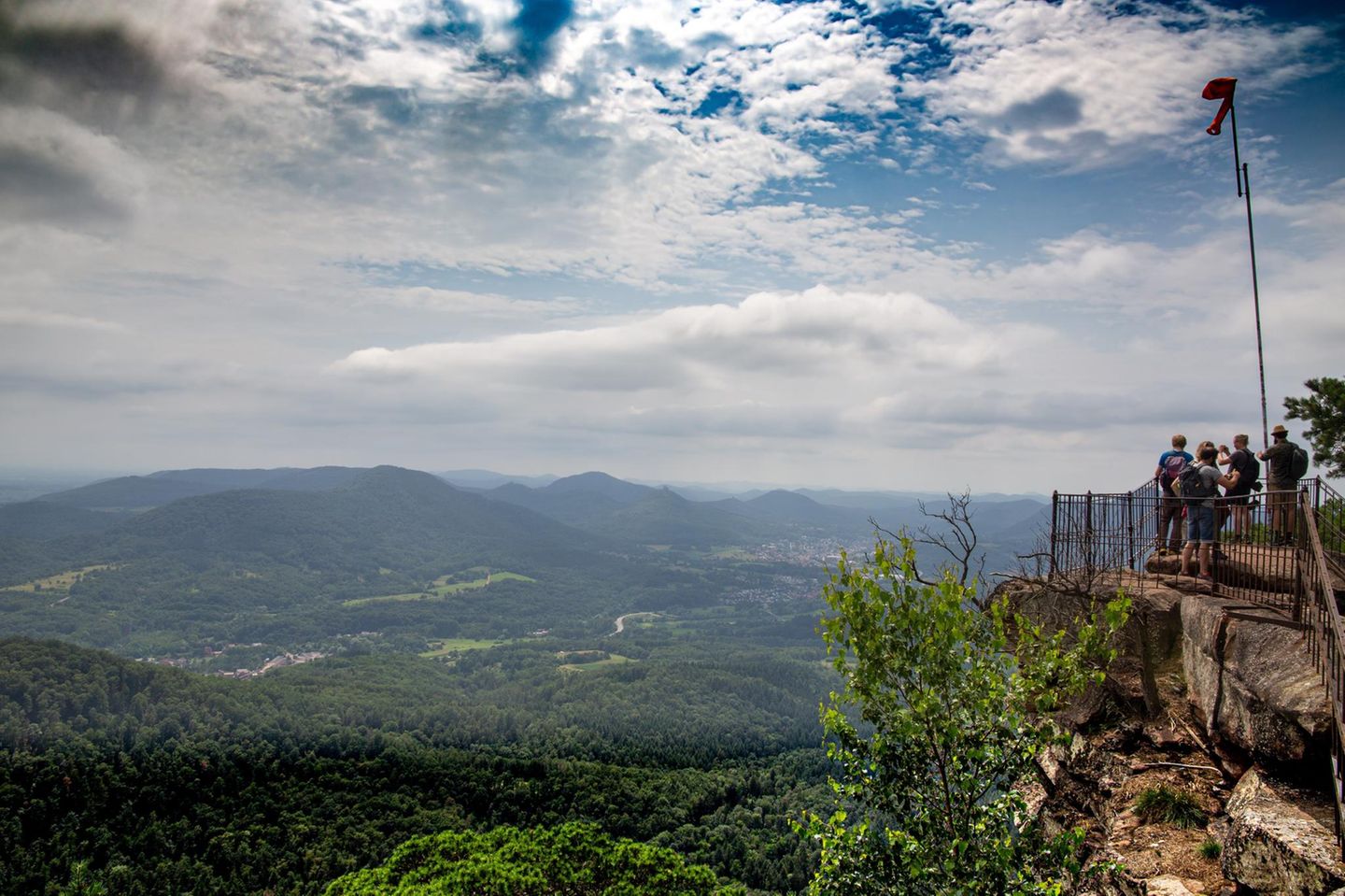 Wanderer auf dem Gipfelplateau Orensfels, dahinter hügelige Landschaft, Himmel mit Wolken