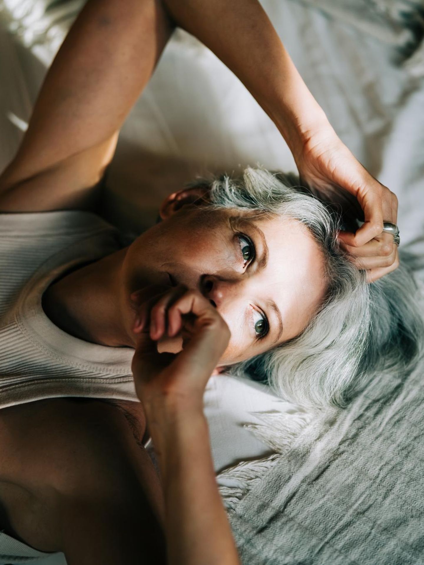 Eine Person mittleren Alters liegt auf dem Bett mit Sonnenstrahlen im Gesicht