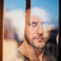 Ein Mann der ernst durch eine Glasscheibe schaut