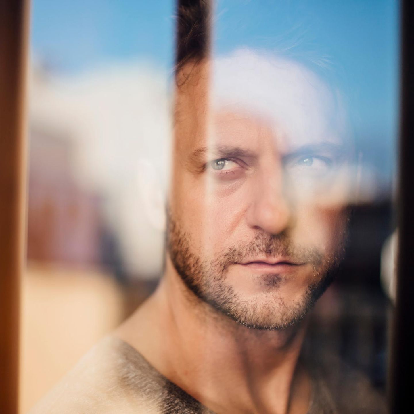 Ein Mann der ernst durch eine Glasscheibe schaut